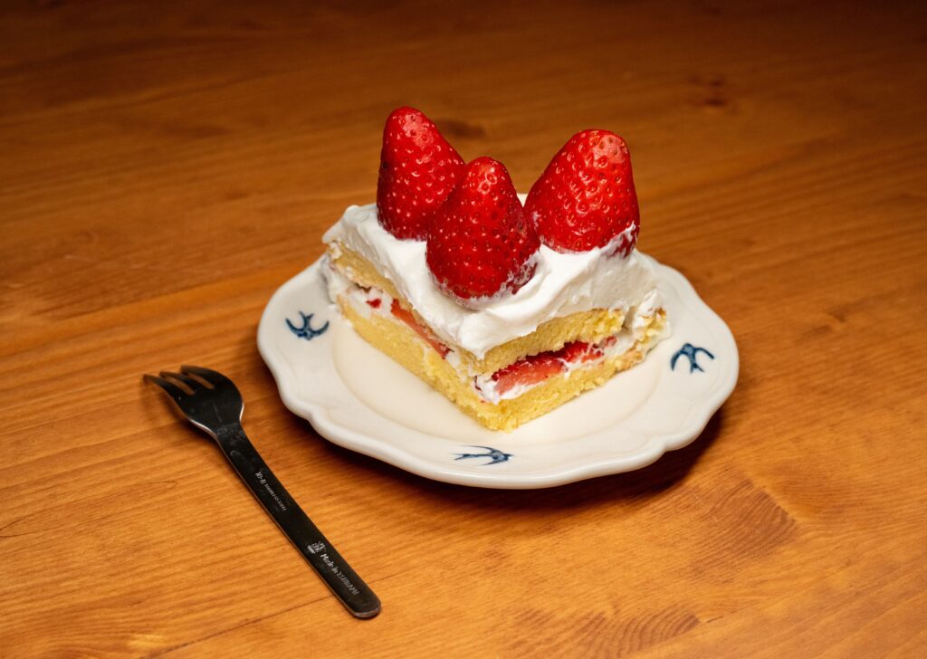 A tempting slice of strawberry shortcake topped with fresh strawberries on a decorative plate.