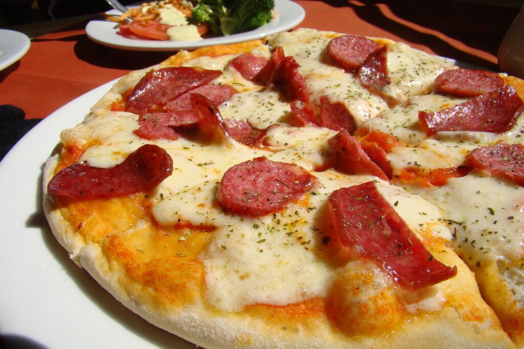 Close-up of a tasty pepperoni pizza with mozzarella cheese and a side salad.